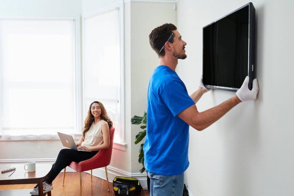 Professional mounting a large television precisely with a laser level